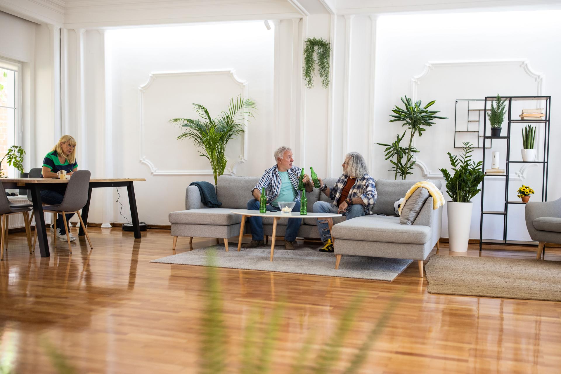 Senior friends watching sport event on tv in living room